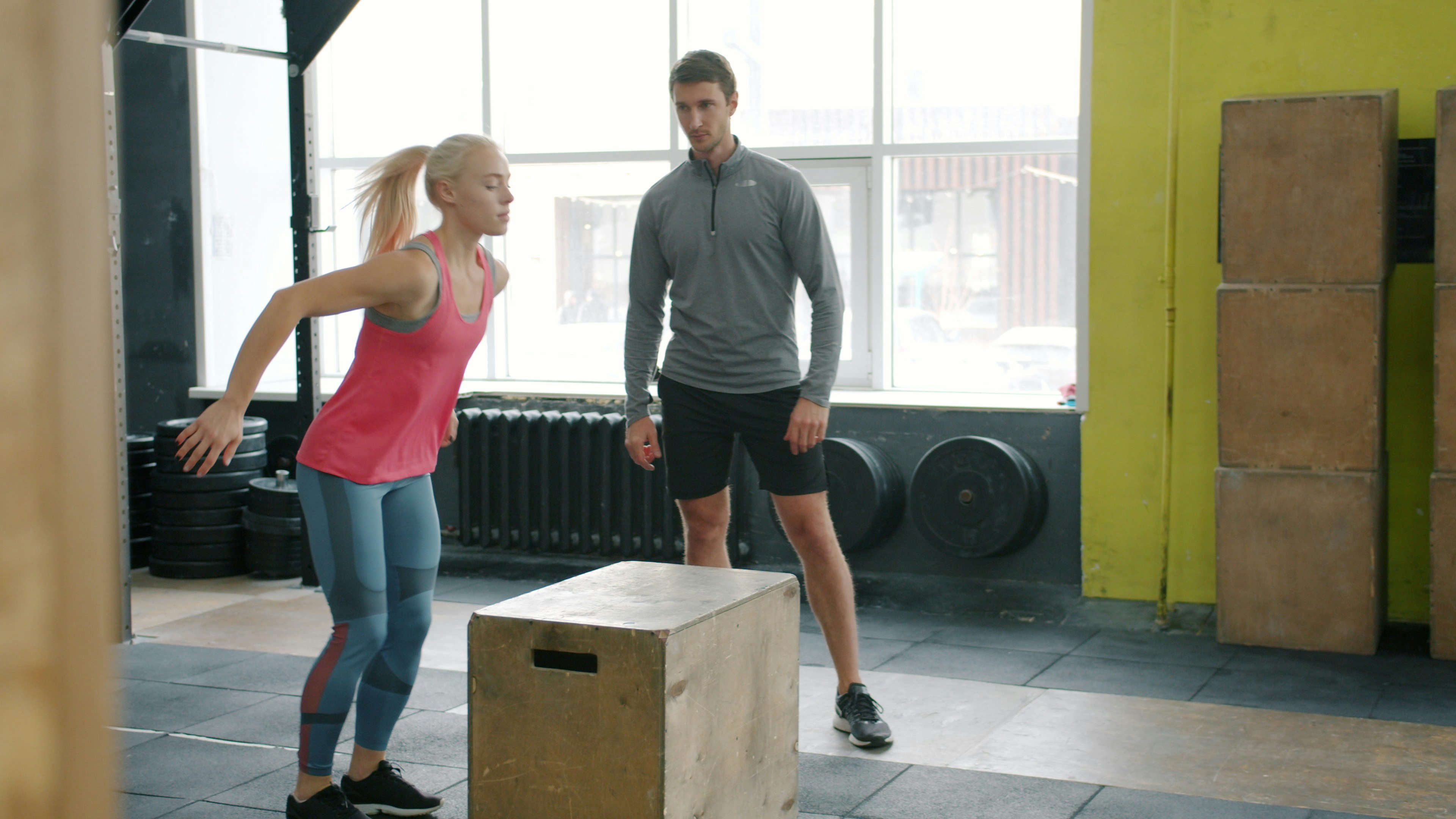 Personal trainer coaching a client during a box jump exercise